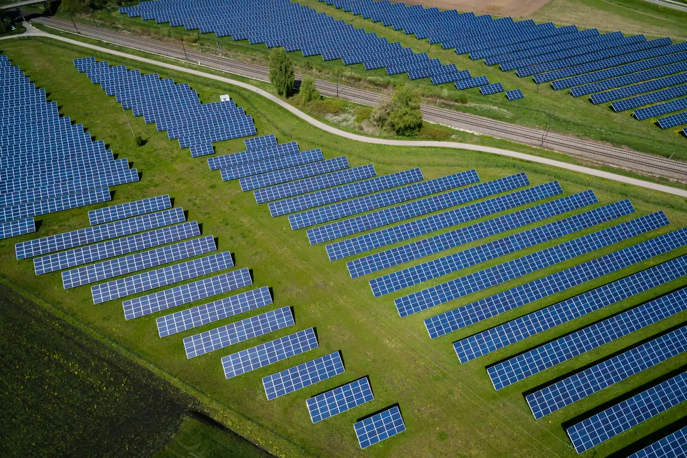 An aerial view of rows of solar panels laid out across green farmland