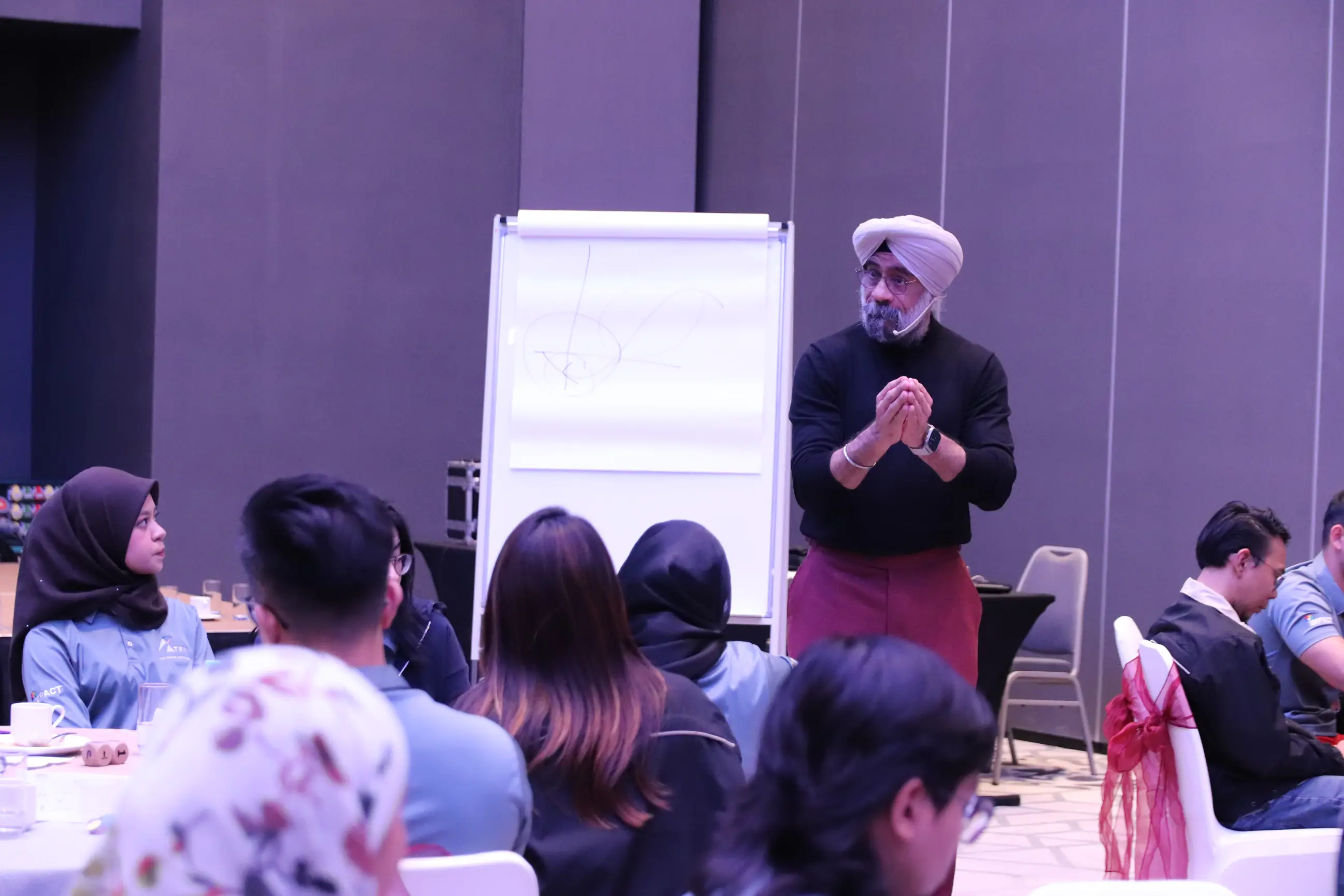 A Learning Edge trainer leading a live team session with a seated cohort gathered around a flipchart